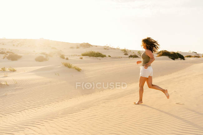 Donna attiva che corre nel deserto secco a piedi nudi — Foto stock