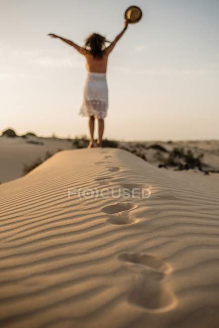 Donna attiva in piedi con cappello a braccia aperte nel deserto secco — Foto stock