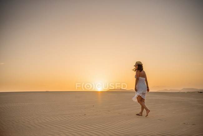 Mujer activa en vestido blanco caminando en desierto seco descalzo - foto de stock