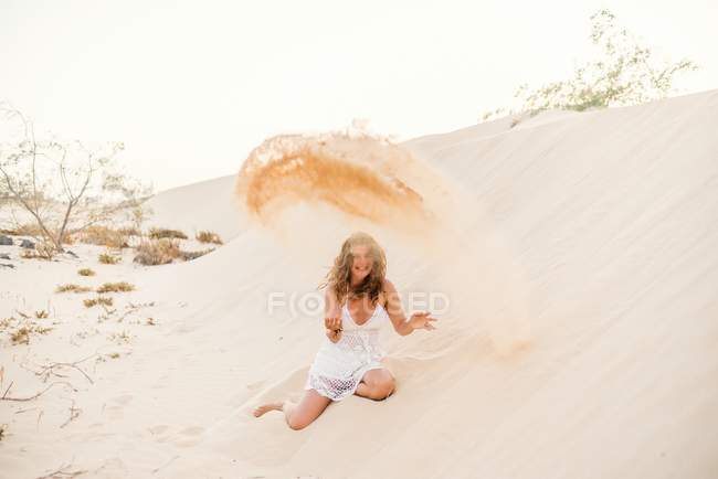 Donna che si diverte a gettare sabbia nel deserto — Foto stock