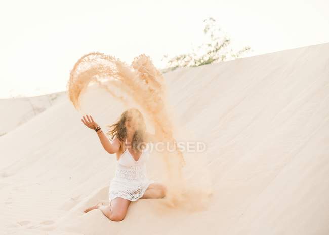 Расслабленная смешная женщина бросает песок на берег в Фуэртевентуре, Лас-Пальмас, Испания — стоковое фото