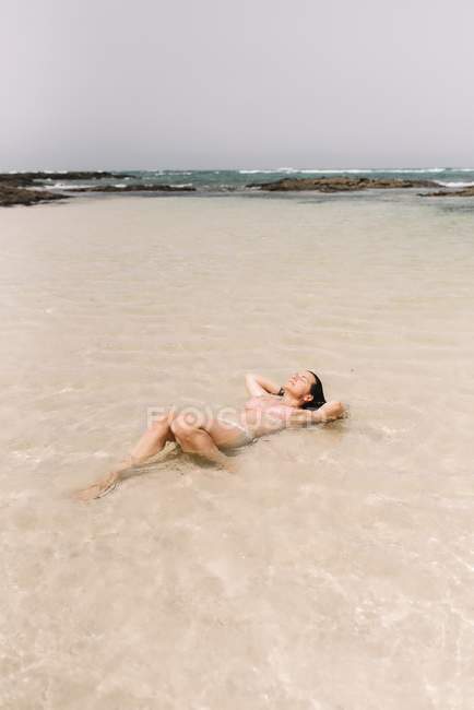 Зверху розслаблена жінка плаває у воді на березі моря у Фуертевентурі (Лас - Пальмас, Іспанія). — стокове фото