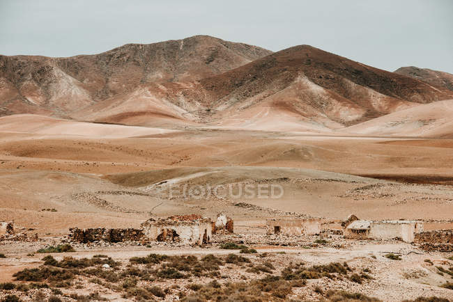 Dilapidated old buildings in mountain desert under cloudy sky — Stock Photo