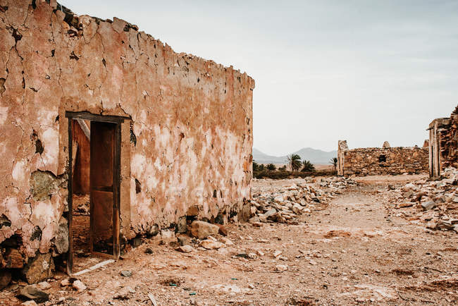 Dilapidated old buildings in mountain desert under cloudy sky — Stock Photo