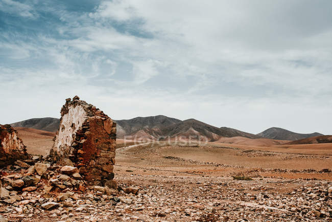 Edificios antiguos dilapidados en el desierto de montaña bajo el cielo nublado - foto de stock