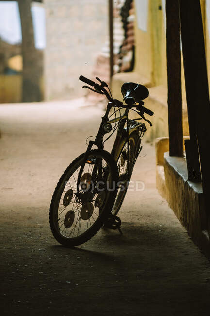 Vélo stationné sur le chemin asphalté dans une ruelle sombre en ville en Gambie — Photo de stock