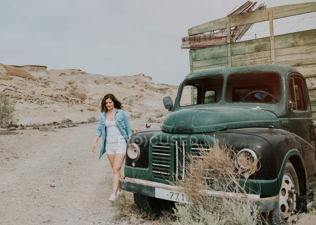 Молодая женщина в шортах и джинсовой рубашке ходит на зеленом грузовике — стоковое фото