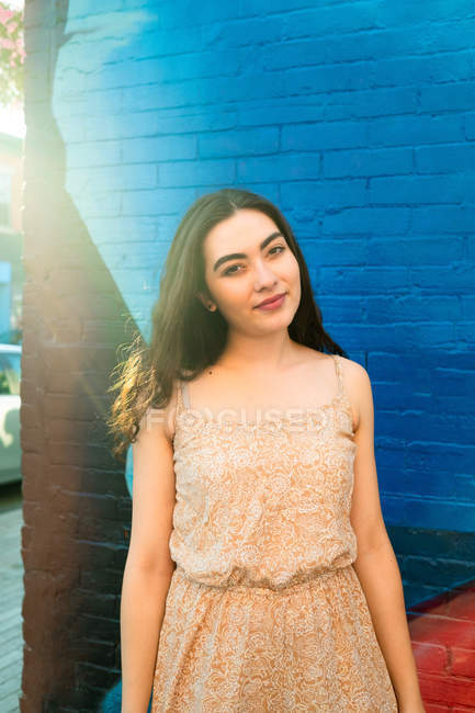 Playful portrait woman in dress smiling while standing by urban brick wall with graffiti — Stock Photo