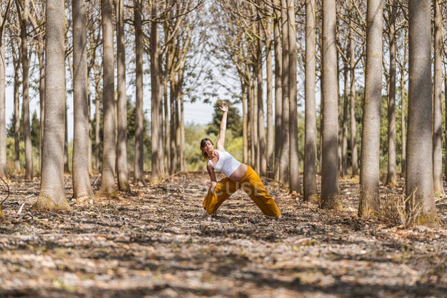 Доросла майбутня мати практикує йогу в парку під час сонячного дня — стокове фото