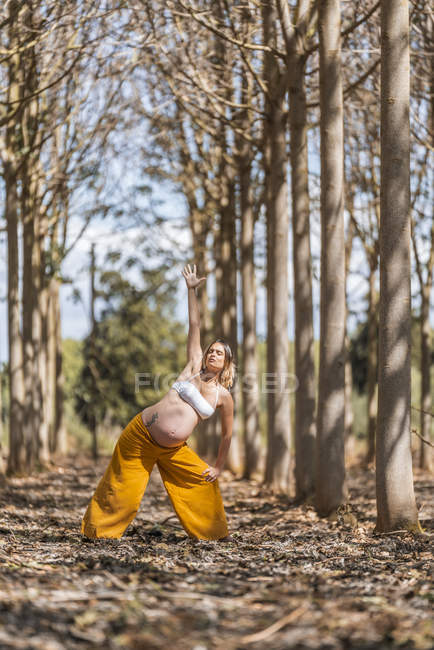 Concentrado adulto expectante mãe praticando ioga no parque — Fotografia de Stock