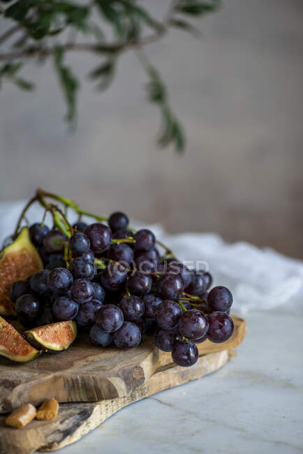 Grapes next to figs on cutting boards near pink flowers — Stock Photo