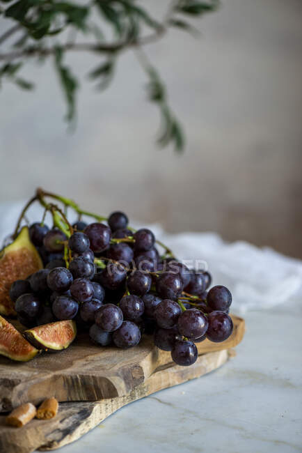 Grapes next to figs on cutting boards near pink flowers — Stock Photo
