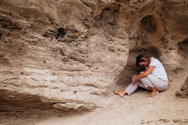 Barfüßige Frau meditiert in Felshöhle — Stockfoto