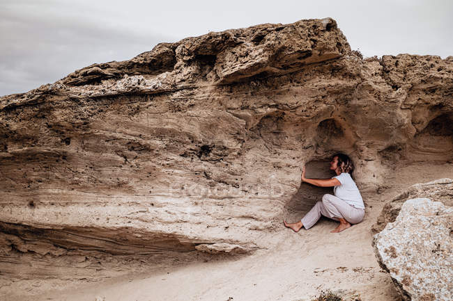 Босоногая женщина медитирует в каменной полости — стоковое фото