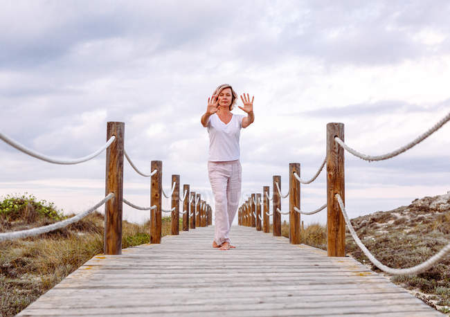 Barefoot woman exercising on wooden path — Stock Photo