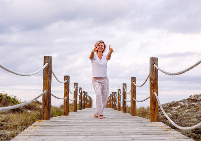 Cheerful woman exercising on timber path — Stock Photo
