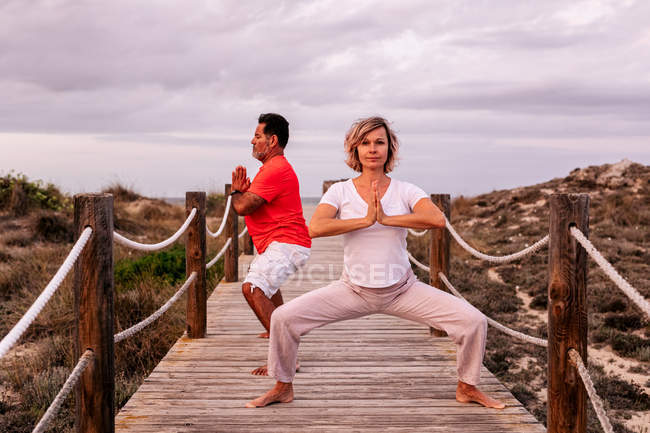 Adult couple meditating on wooden path — Stock Photo