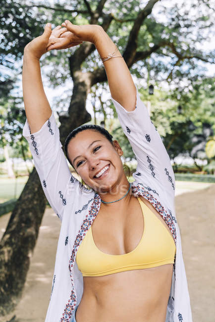 Femme joyeuse en bikini souriant et debout les mains en l'air, regardant loin dans la rue au Costa Rica — Photo de stock