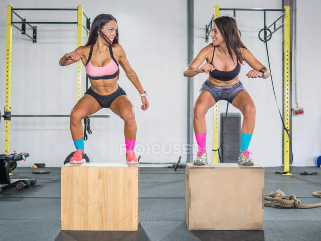 Frohe Sportlerinnen unterhalten sich beim Training im modernen Fitnessstudio — Stockfoto