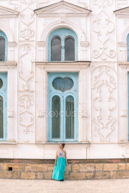 Lady in dress walking down steps outside shabby ornamental building on sunny day in Bukhara, Uzbekistan — Stock Photo