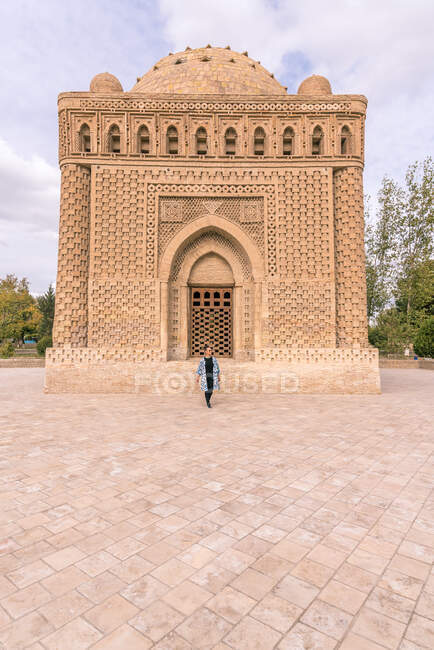 Female walking on pavement outside ancient traditional building during trip in Bukhara, Uzbekistan — Stock Photo