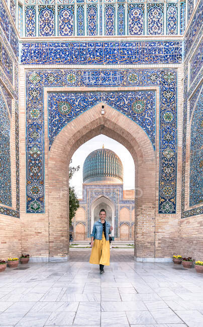 Visão traseira da mulher irreconhecível em pé na entrada do edifício ornamental pobre em Samarcanda, Uzbequistão — Fotografia de Stock