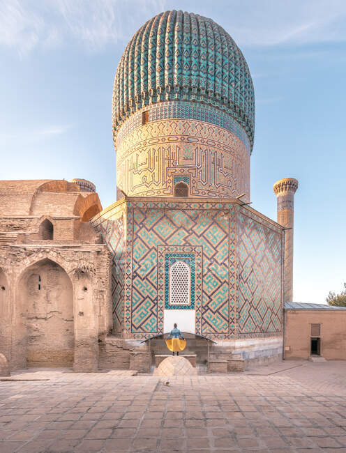 Vista posteriore di donna anonima in piedi fuori Gur-e Amir mausoleo con bellissimi ornamenti e cupola nella giornata di sole in Samarcanda, Uzbekistan — Foto stock
