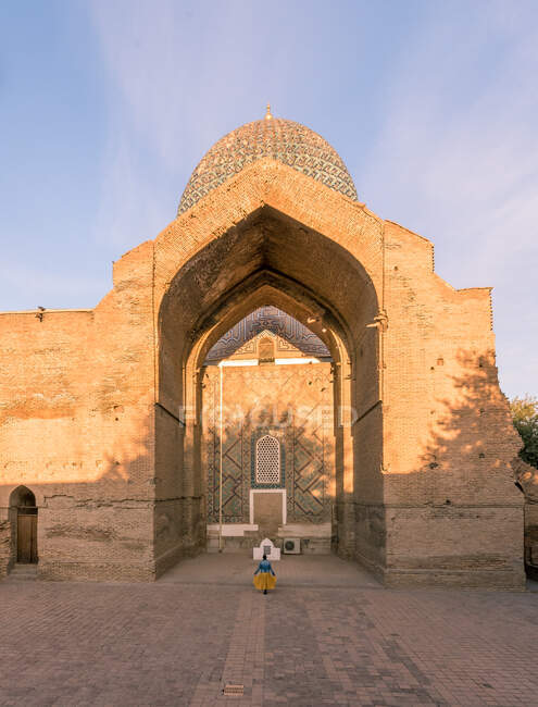 Visão traseira da mulher irreconhecível em pé na entrada do edifício ornamental pobre em Samarcanda, Uzbequistão — Fotografia de Stock