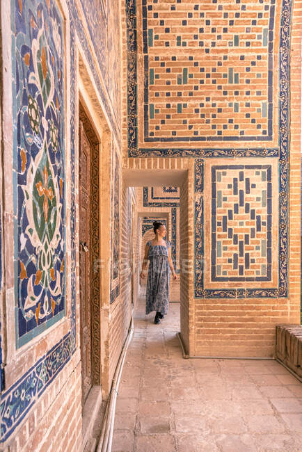 Mujer admirando los ornamentos en las paredes del antiguo edificio mientras visita Samarcanda, Uzbekistán - foto de stock