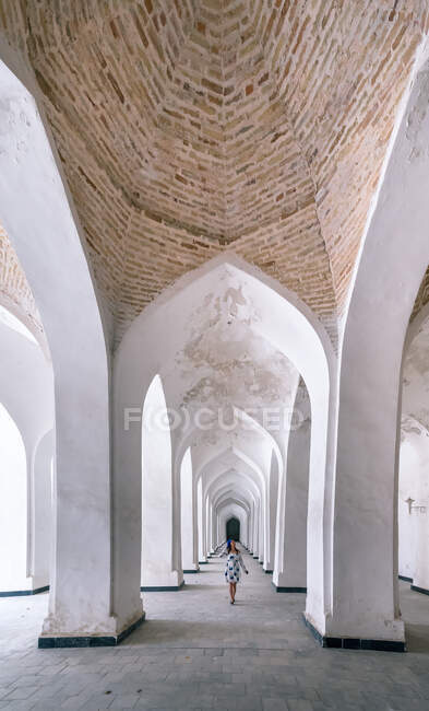 Female traveler walking in arched passage of old building during trip in Bukhara, Uzbekistan — Stock Photo