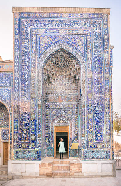 Mujer de pie en la puerta del edificio ornamental de mala calidad de la necrópolis islámica de Shah-i-Zinda en Samarcanda, Uzbekistán - foto de stock