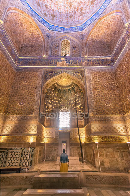 Vue arrière de la femme anonyme admirant les ornements sur les murs de l'ancien bâtiment lors de la visite du mausolée Gur-e Amir à Samarkand, en Ouzbékistan — Photo de stock