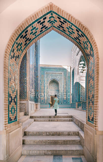 Vue arrière du voyageur féminin marchant dans le passage voûté de l'ancien bâtiment pendant le voyage en Ouzbékistan — Photo de stock