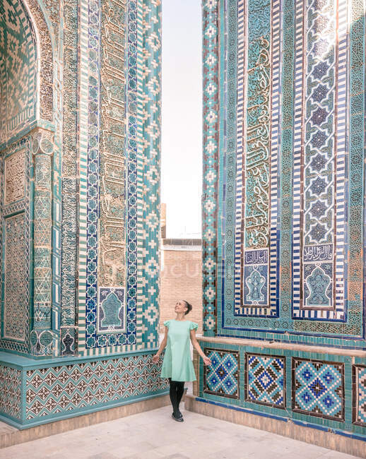 Mujer admirando los ornamentos en las paredes del antiguo edificio mientras visita Samarcanda, Uzbekistán - foto de stock