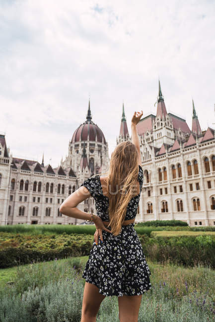 Long-haired woman raising hand to ancient old building in Budapest — Stock Photo