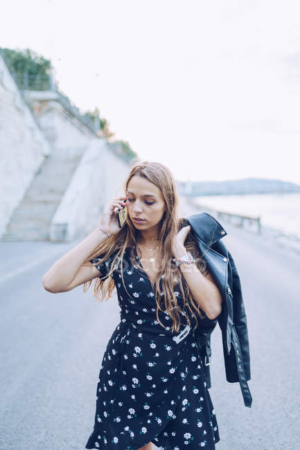 Длинноволосая стильная женщина говорит на смартфоне в Будапеште — стоковое фото