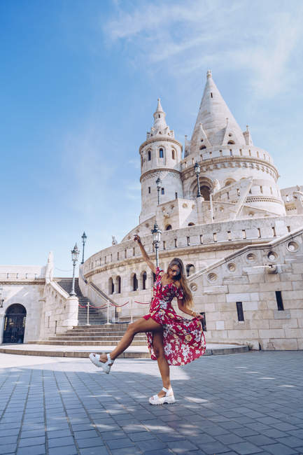 Mulher elegante alegre se divertindo na praça com edifício antigo com torres pontiagudas e cúpulas em Budapeste — Fotografia de Stock
