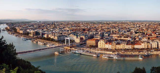Barcos en el canal de la ciudad que fluyen bajo el puente en el día brillante en Budapest - foto de stock