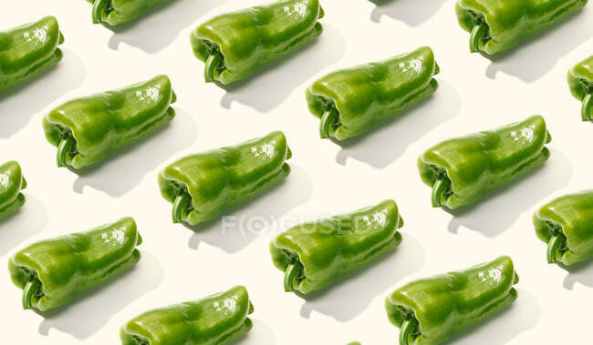 Dall'alto composizione creativa di pepe intero verde a fette su superficie bianca — Foto stock