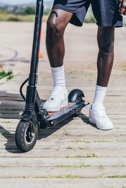 Підозрюваний образ афроамериканського спортсмена, який їде на електричному скутері в ясний похмурий день. — стокове фото