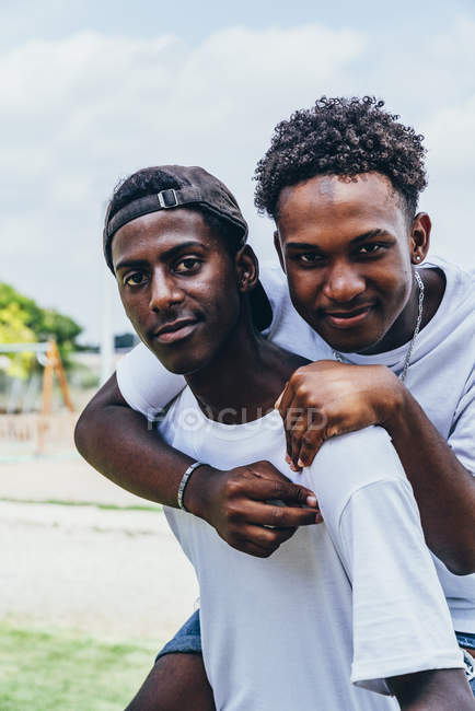 Joyeux câlin afro-américains jeunes hommes regardant la caméra et des gestes — Photo de stock