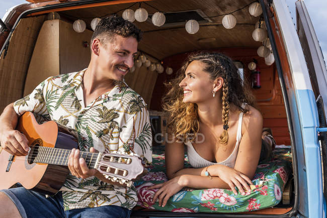 Alegre macio casal no tronco de carro se divertindo juntos tocando na guitarra e desfrutar de música — Fotografia de Stock
