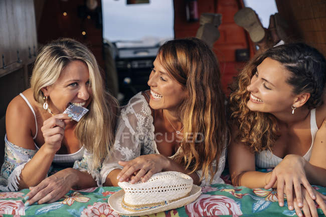 Gioioso amici di sesso femminile discutendo e mostrando preservativo mentre si trova nel bagagliaio della macchina — Foto stock