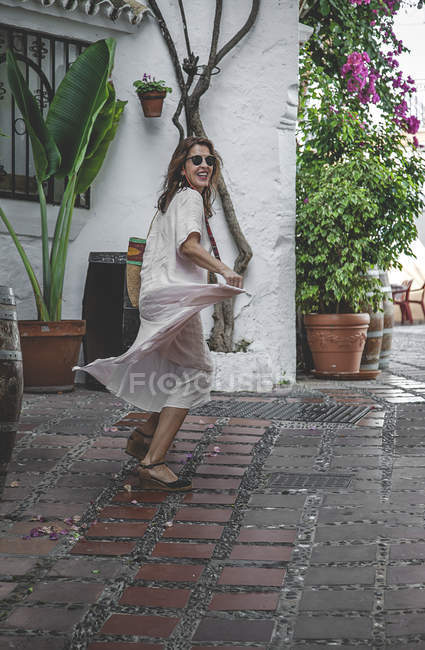 Vista lateral da mulher entusiasta positivo na moda com saco de verão apreciando passear na backstreet de Marbella — Fotografia de Stock