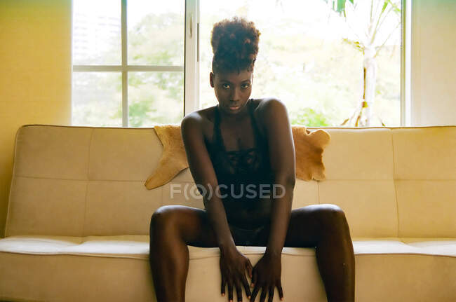 Femme afro-américaine élégante en lingerie sur canapé — Photo de stock