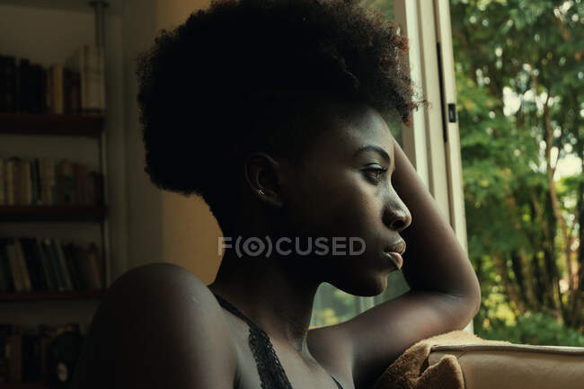 Mujer negra apoyada en una ventana - foto de stock