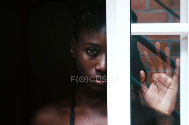 Upset black female standing behind window — Stock Photo