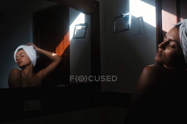 Sereno sensual mulher nua contra espelho no banheiro — Fotografia de Stock