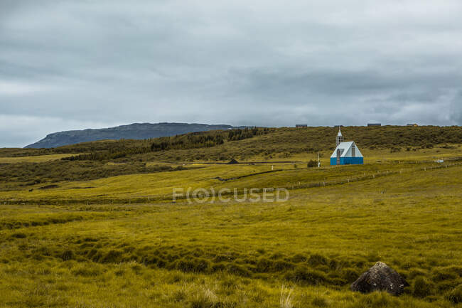 Pintoresco paisaje de acogedora casa linda en campo verde sin fin en Islandia en día nublado en Islandia - foto de stock