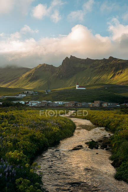 Pintoresco paisaje de sendero entre acogedoras casas lindas en valle de montaña en Islandia en día nublado - foto de stock